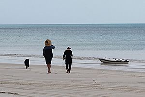 Image of a person taking their dog onto the beach at K’gari (Fraser Island).
