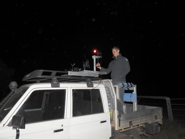 Image of a ranger at night on the back of a 4WD ute using a thermal camera for the monitoring and protection of the bridle nail-tail wallaby population.
