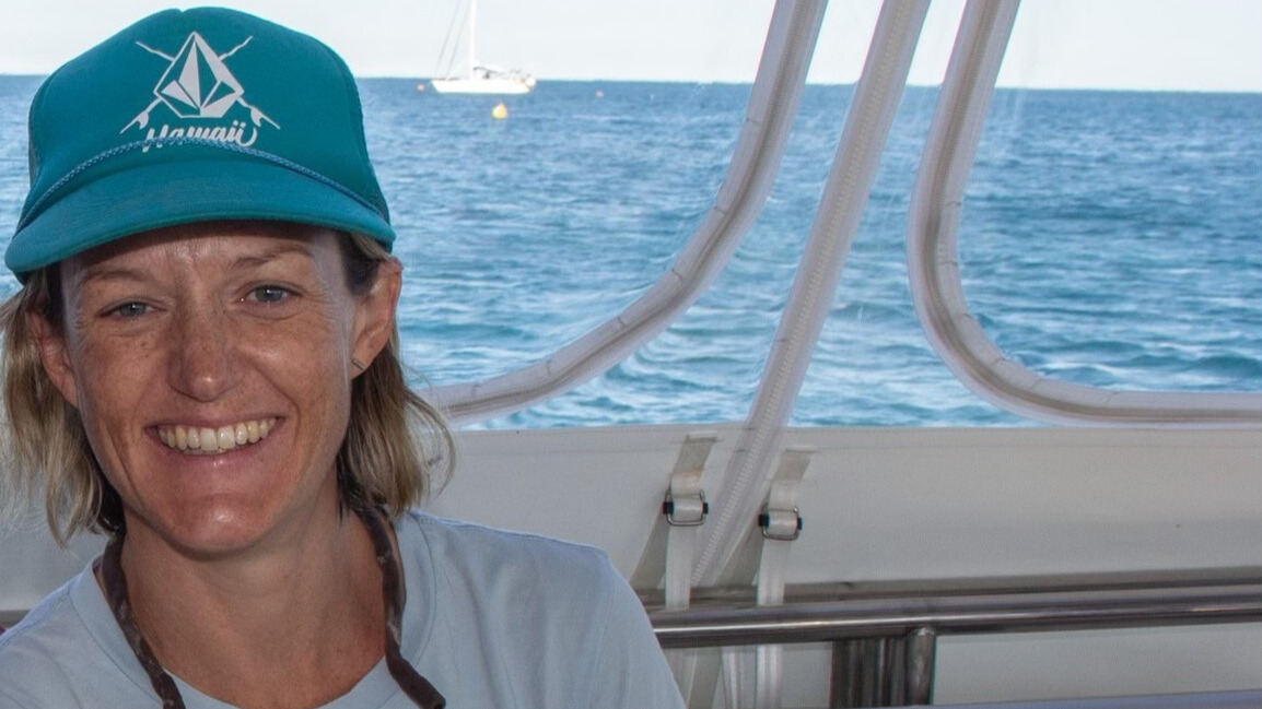 Close-cropped landscape headshot of a woman with shoulder-length blonde hair wearing a turquoise cap on a boat with crisp blue ocean in the background.