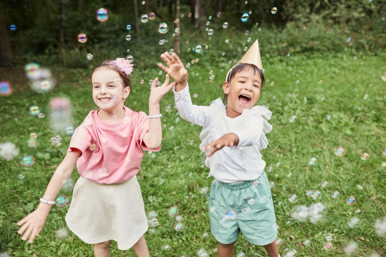 Girls playing with bubbles while enjoying Birthday party outdoors in Summer.