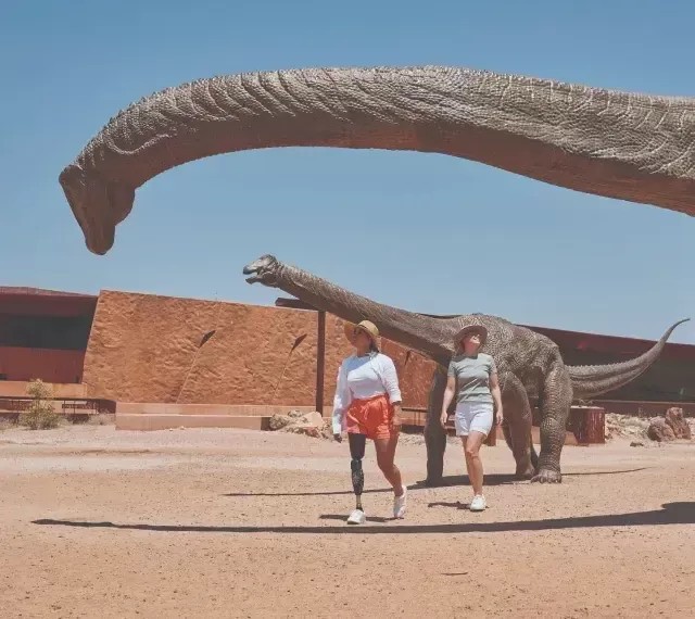 Photo of people walking through an exhibition of life-sized replica dinosaurs