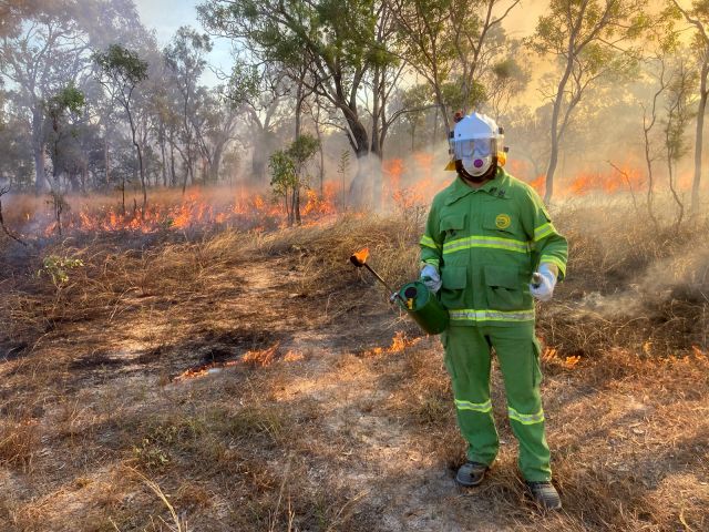 Photo of Ranger Hayden conducting a planned burn as part of fire training on Yunbenun (Magnetic Island).
