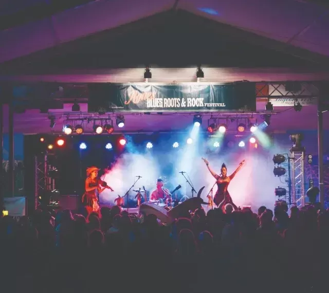 Photo of musical artists on stage at outdoor concert with extreme lighting