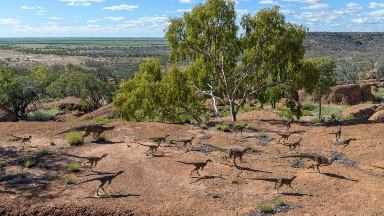 A flock of small dinosaur sculptures spread out across a red desert landscape.
