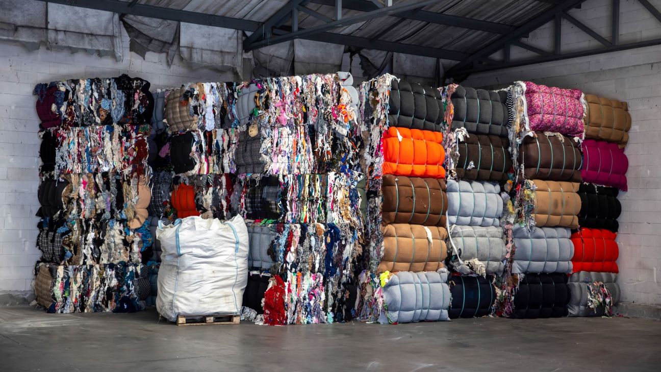 Heap of pressed colourful textile waste packed in bales in a storehouse.