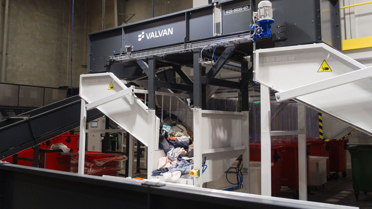 Assorted clothes and textiles travelling down a ramp on a piece of machinery designed to identify and categorise textiles. 