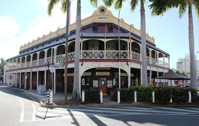 A large two-storey cream and brown building on a corner block with an ornate wraparound verandah.