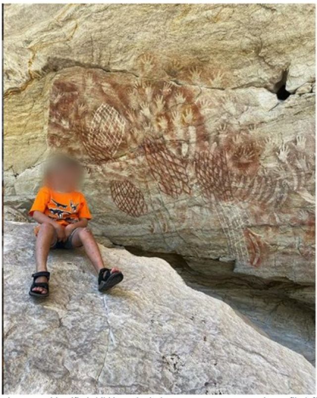 Photo of a boy in front of the rock art. His parents received a fine.