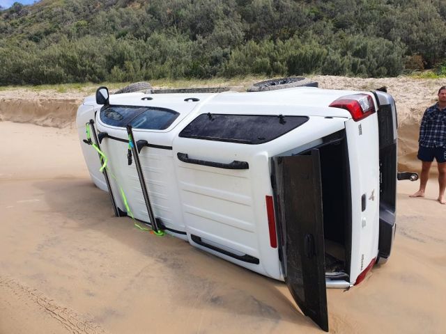 Photo of a white car that rolled off the dunes and straight into the ocean.